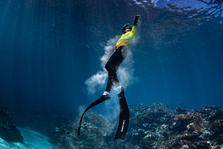 a man flying through the air while swimming in a body of water
