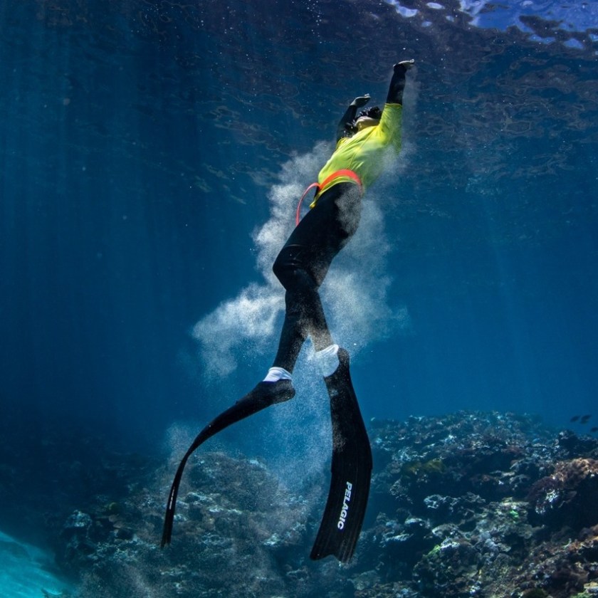 a man flying through the air while swimming in a body of water